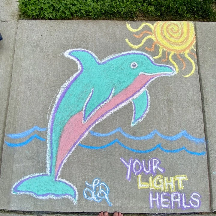 Chalk drawing of a dolphin with the words 'Your light heals'