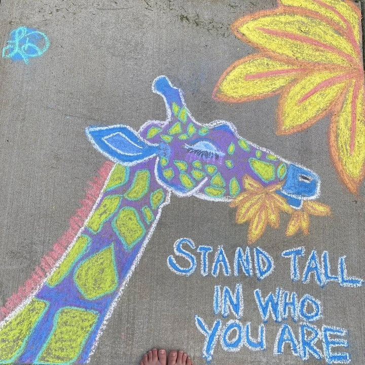 Chalk drawing of a giraffe with the words 'Stand tall in who you are'